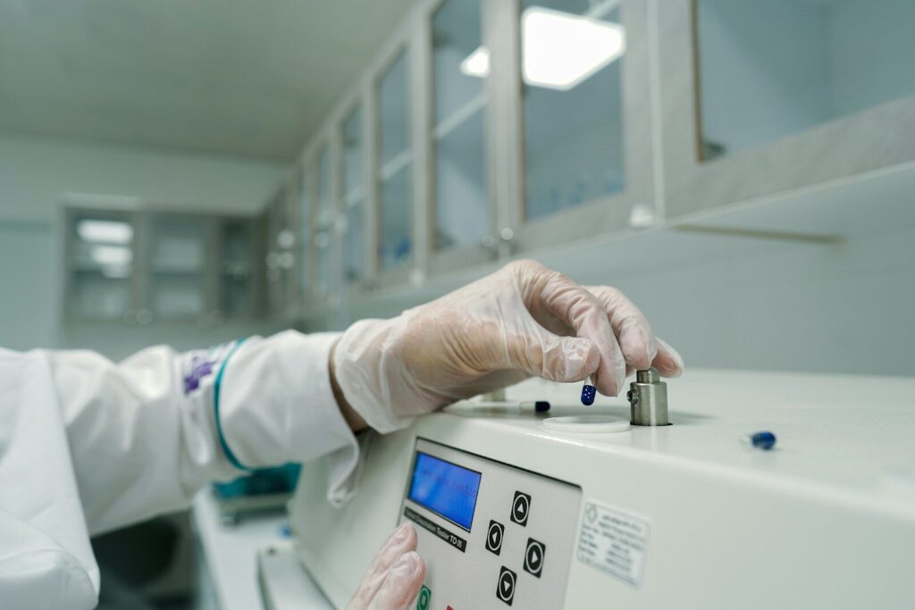 A person in a lab coat and gloves working on a machine